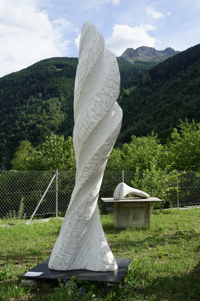 Gewundene Skulptur vor Berglandschaft